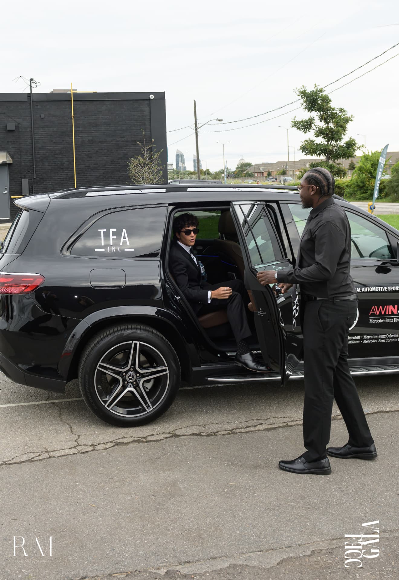 Eminent Valet chauffeur opening the rear door of a black Mercedes SUV for a guest